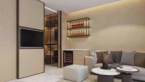 A modern living room with a sofa, ottoman, coffee table, and a TV. - The Five Hotel & Resort Evara - 24 Hours stay (Hanoi)