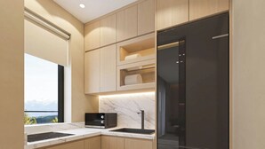 A modern kitchen with wooden cabinets, a black refrigerator, and a built-in oven. - The Five Hotel & Resort Evara - 24 Hours stay (Hanoi)