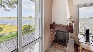Una habitación con chimenea, un escritorio con ordenador y vistas a un lago.