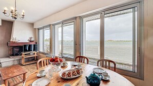 Un comedor con vistas a un cuerpo de agua, una chimenea y un candelabro.