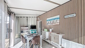 Una stanza compatta con tavolo e sedie, televisione, un angolo cottura e una parete in legno decorata con un quadro.