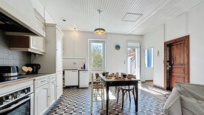 Una cocina con piso de baldosas, un comedor con mesa y sillas, y una puerta de madera.