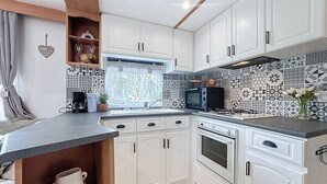 Een kleine keuken met witte kastjes, een magnetron, een oven en een spoelbak.