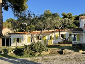 A white building with green shutters, a tiled roof, and a gravel driveway. - Colibri 2 By ColombiElbaVacanze - Colibrì 2 (Capoliveri)