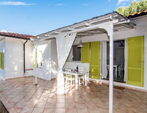 A covered patio area with a table and chairs, a white ceiling structure, and green shutters on the walls. - Colibri 2 By ColombiElbaVacanze - Colibrì 2 (Capoliveri)