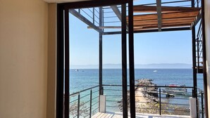 A room with a ceiling fan, large sliding glass doors leading to a balcony with a view of the sea and boats. - Amaizing View Islas Marietas (Punta de Mita)