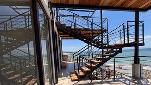 A modern building with a wooden staircase leading to a balcony overlooking the ocean. - Amaizing View Islas Marietas (Punta de Mita)