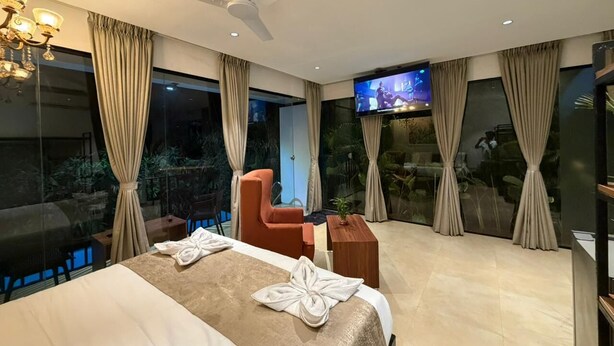 A hotel room with a bed, a TV, a ceiling fan, and a view of the outdoors. - 7 Tree Resort & Restaurant (Paud)