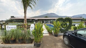 A nursery with a sign indicating it is open, potted plants, a statue, and a car parked in front. - 7 Tree Resort & Restaurant (Paud)