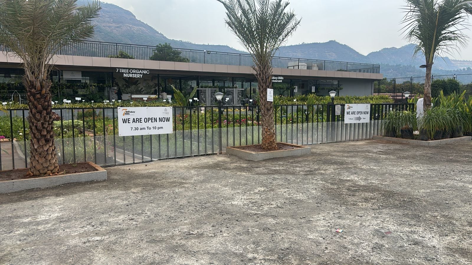 A gated nursery with signs indicating it is open from 7:30 am to 10 pm.