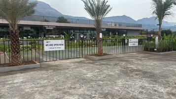 A gated nursery with signs indicating it is open from 7:30 am to 10 pm.