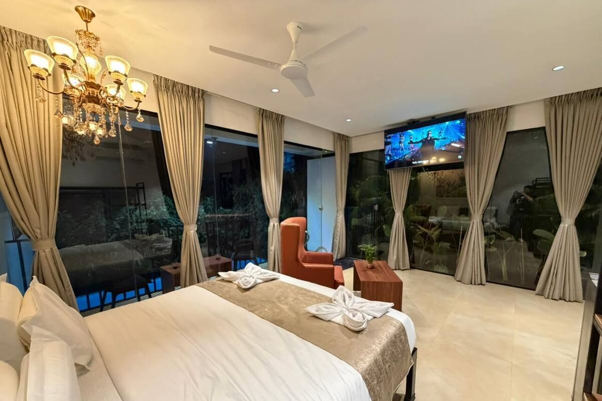 A modern hotel room with a large bed, a ceiling fan, a TV, and a view of the outdoors.