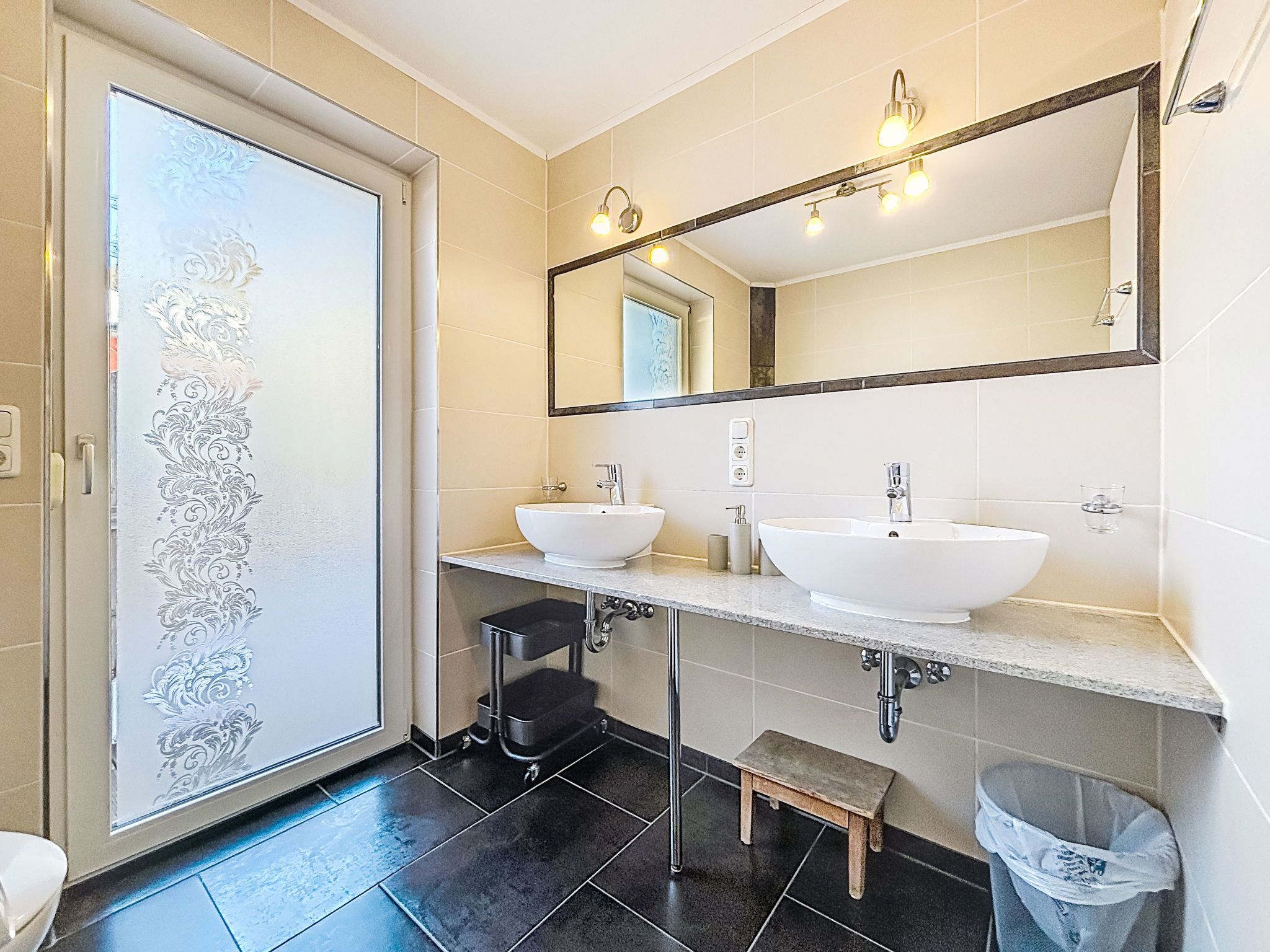 A bathroom with two sinks, a mirror, and a shower.