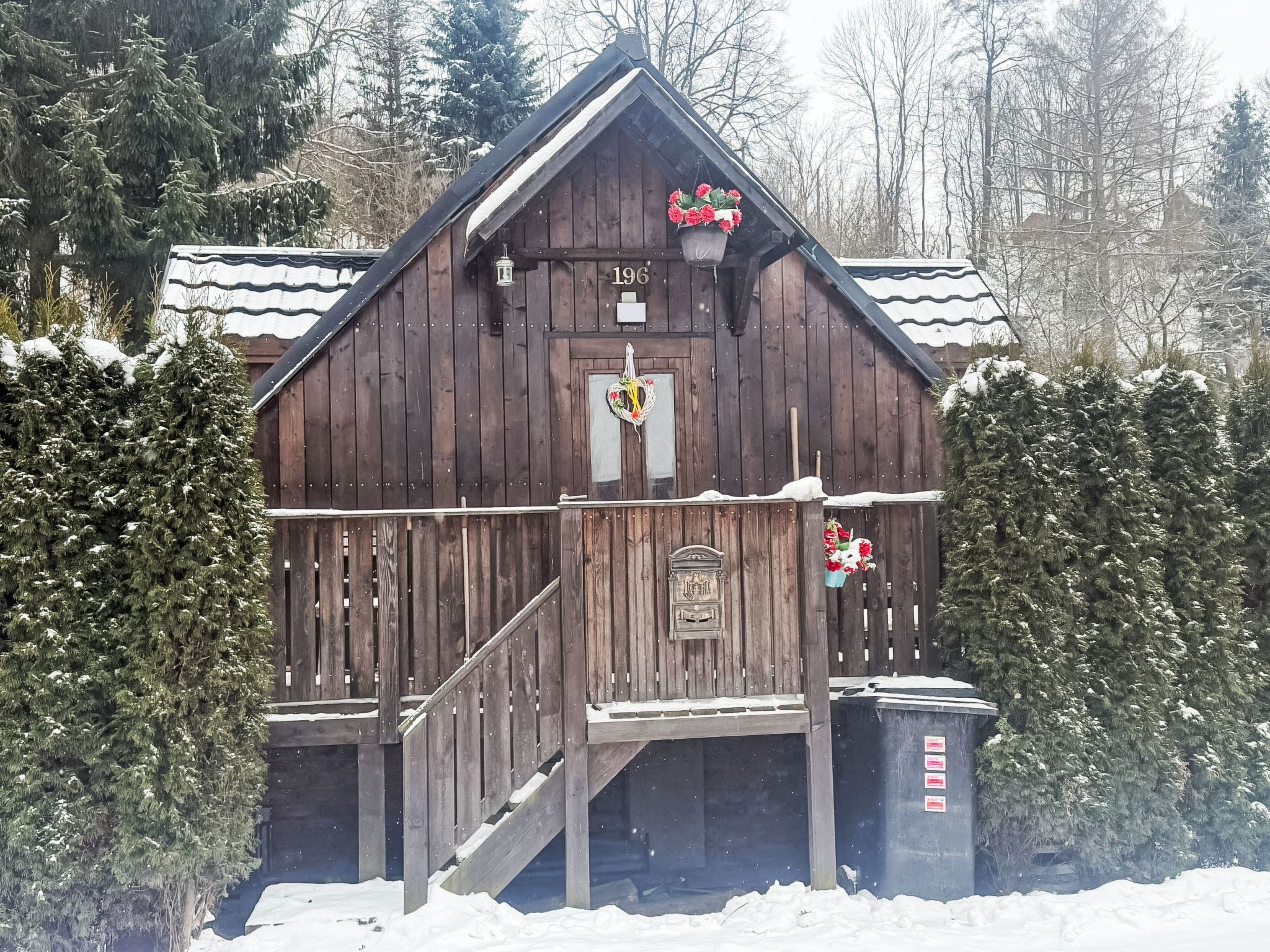 En træhytte med nummer '196' på forsiden, en veranda og en postkasse.