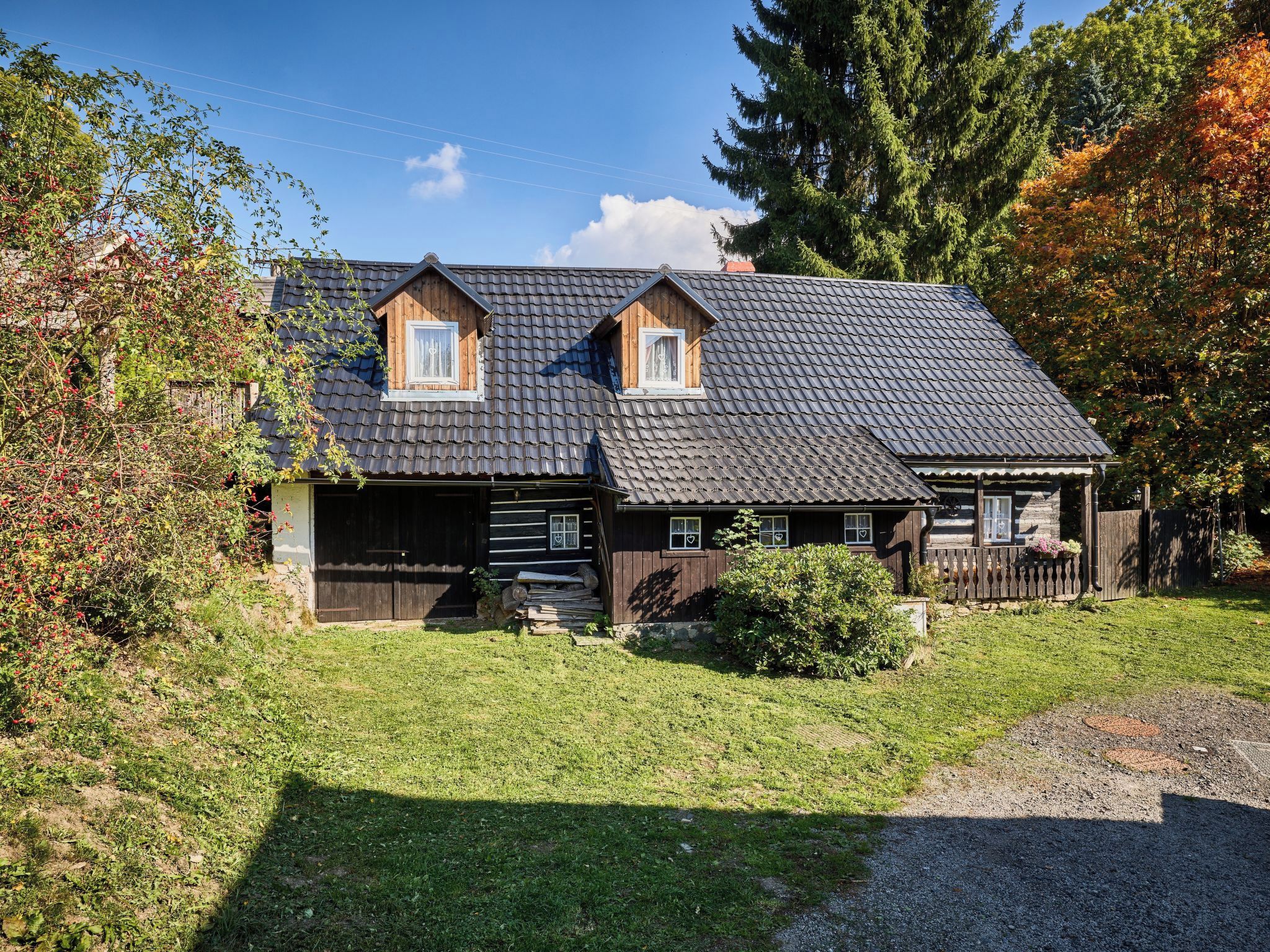 Ein zweistöckiges Holzhaus mit Satteldach, einer Veranda und einem eingezäunten Garten.