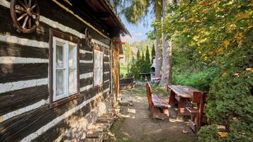 Une cabane rustique en rondins de bois, dotée d’un porche en bois, d’un banc et d’une table de pique-nique.