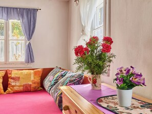 A room with a bed, a table with a vase of flowers, and a window with curtains. - Roubenka u potoka by Interhome (Výprachtice)