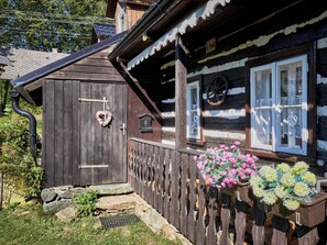 A wooden house with a sloped roof, a wooden fence, and flower boxes with flowers. - Roubenka u potoka by Interhome (Výprachtice)