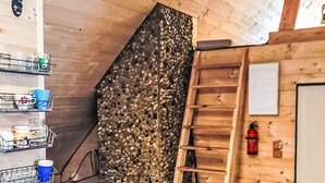 Un interior de madera con una cuna, estantes con vajilla, una escalera y una puerta.