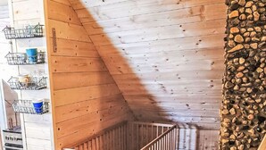 Una cuna de madera en un dormitorio tipo buhardilla con techo inclinado y pared de piedra.