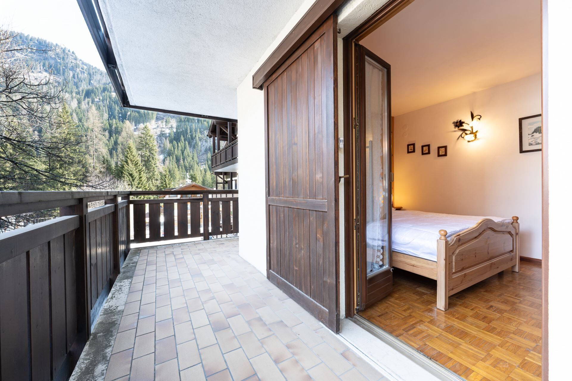 Ein Schlafzimmer mit einem Holzbett, einem Balkon mit Holzgeländer und Blick auf die Berge.