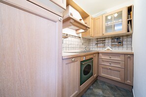 Eine Küche mit Holzausstattung, einem Einbauofen und einer gefliesten Spritzschutzwand.