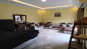 A living room with a sofa, a chair, a small table, and a TV. - Cozzy Villa Garden Jogja  (Kalasan)