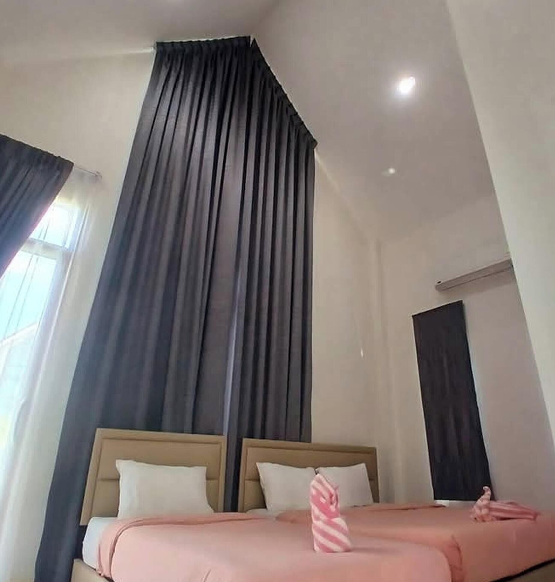 Habitación de hotel con dos camas, cortinas oscuras, una lámpara en el techo y una ventana.