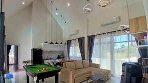 A spacious living area with a pool table, sofa, and television.