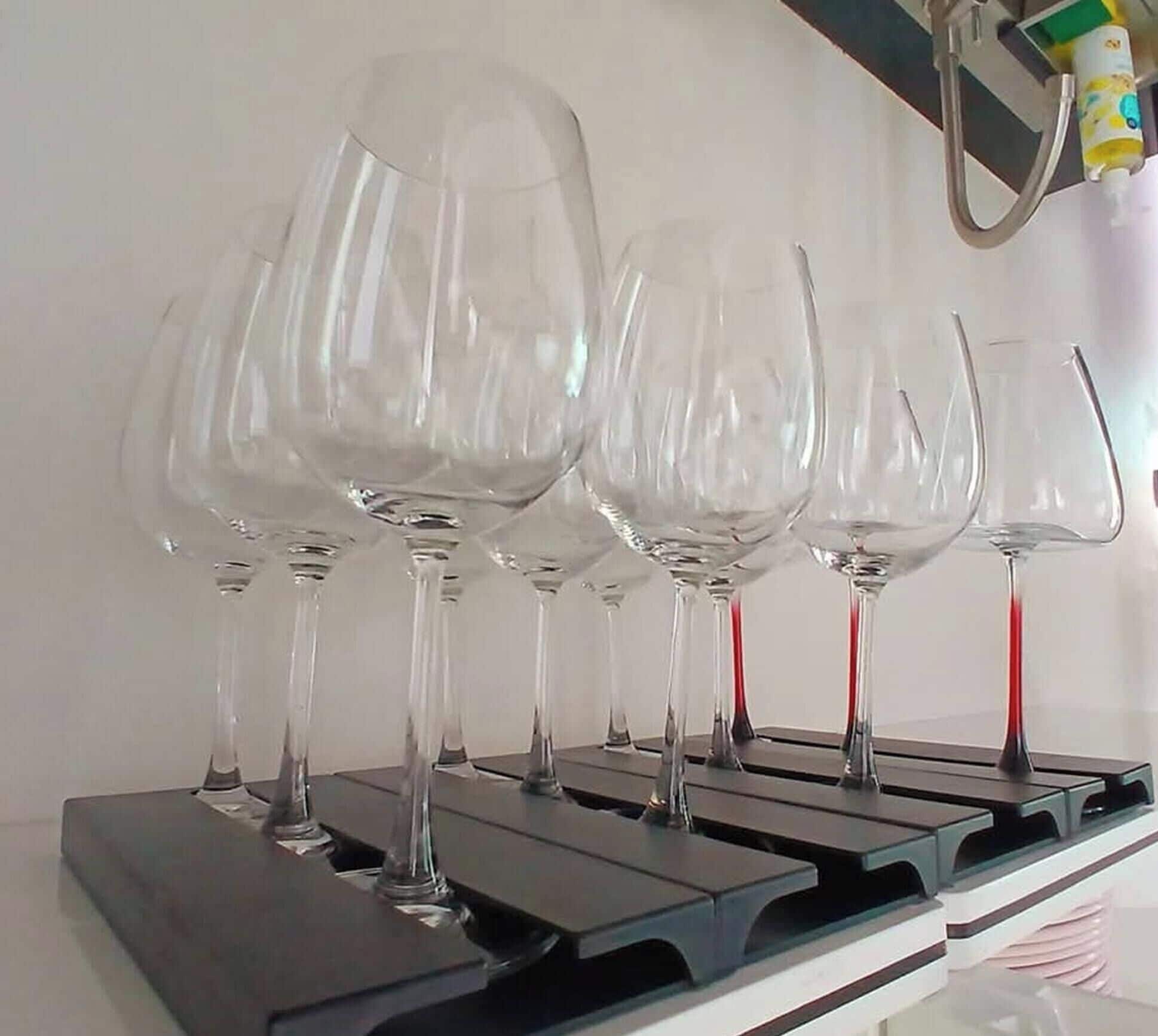 A kitchen with a stainless steel range hood and a row of wine glasses hanging from it.