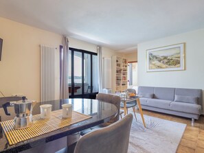 Ein modernes Wohnzimmer mit Essbereich, einer Couch, einem Bücherregal und einem Gemälde an der Wand.