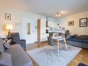 A modern living room with a sofa, a dining table, and a kitchen area. - Leonard Lake by Interhome (Ghiffa)