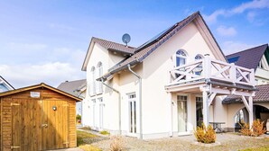 A two-story house with a balcony, a wooden garage, and a paved driveway. - Appartement in Zinnowitz mit Grill by Interhome (Zinnowitz)