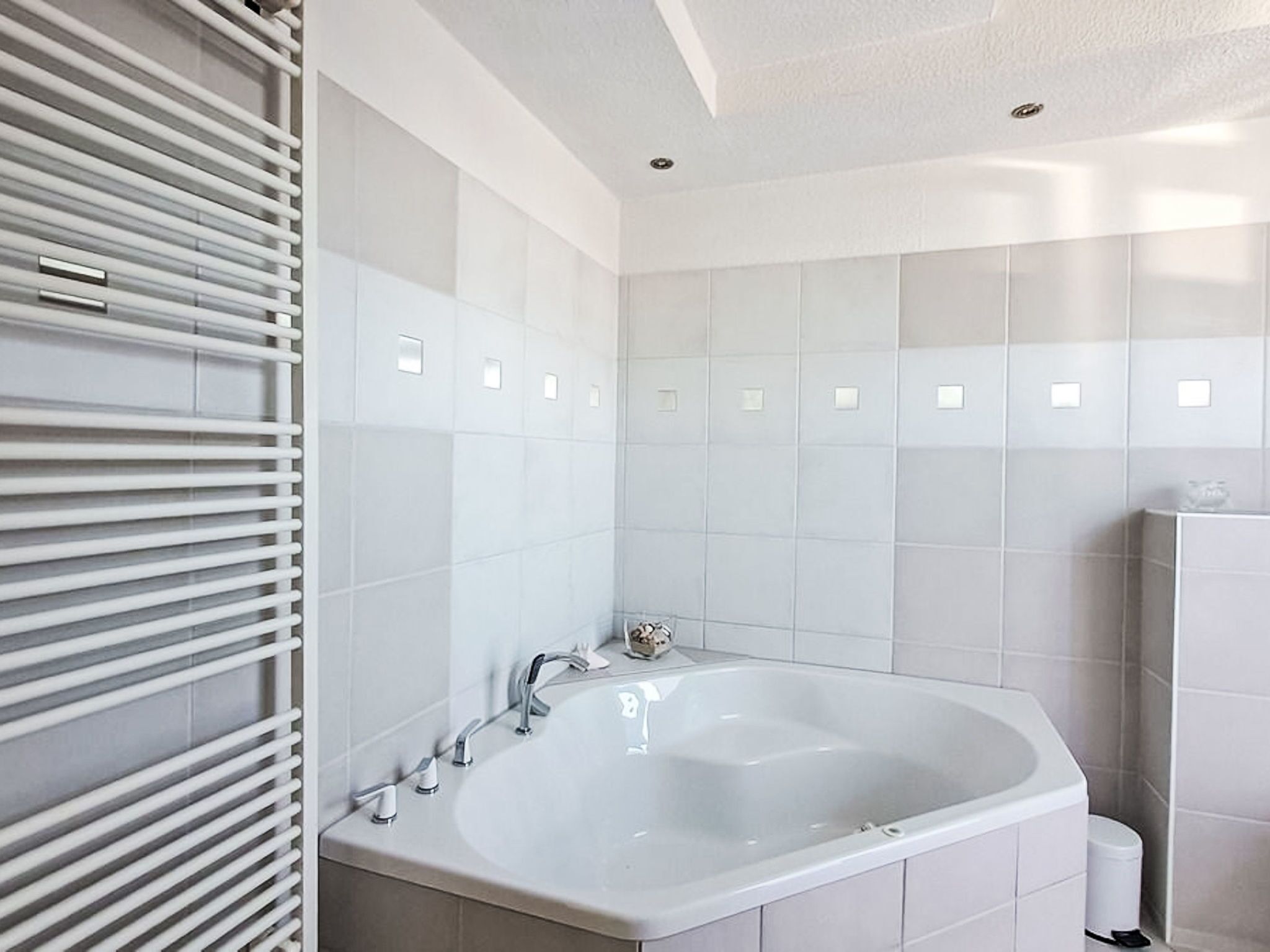 Une salle de bain moderne avec une baignoire sur pieds, des carreaux blancs et un porte-serviettes.