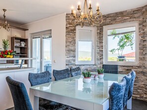 A modern kitchen with a stone wall, a glass dining table, and a chandelier. - Holiday Home Meri by Interhome (Pridraga)