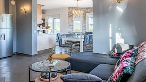 Ein modernes Wohnzimmer mit Sofa, Couchtisch und Blick auf die Küche und den Essbereich.