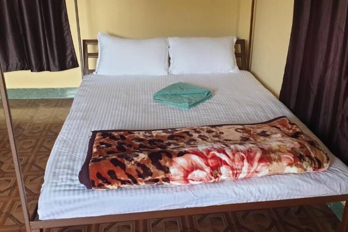 A bed with a patterned bedspread, two pillows, and a folded towel.