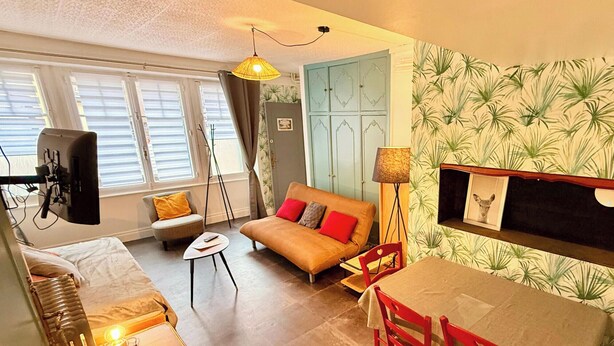 Un salon comprenant un canapé, une table avec des chaises, un téléviseur et une lampe.