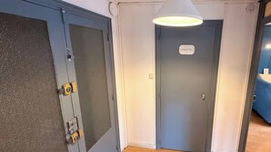 A hallway with a door labeled 'TOILETTES,' a grey door with a textured surface, and a white ceiling light fixture. - Le marcassin Le Mont Dore 8pers (Mont-Dore)