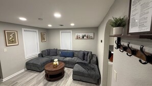 A living room with a sectional sofa, a round coffee table, and a wall-mounted plant shelf.