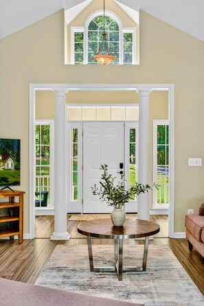 A spacious entryway with a high ceiling, a large window, and a door with glass panels. - Hello Sunshine | 6BR Lakefront Lake Anna | Dock, Fire Pit & Game Room (Mineral)