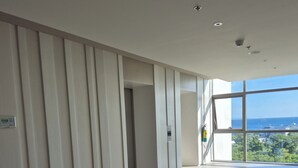 Une pièce spacieuse avec une grande fenêtre, une porte et un interrupteur sur le mur.
