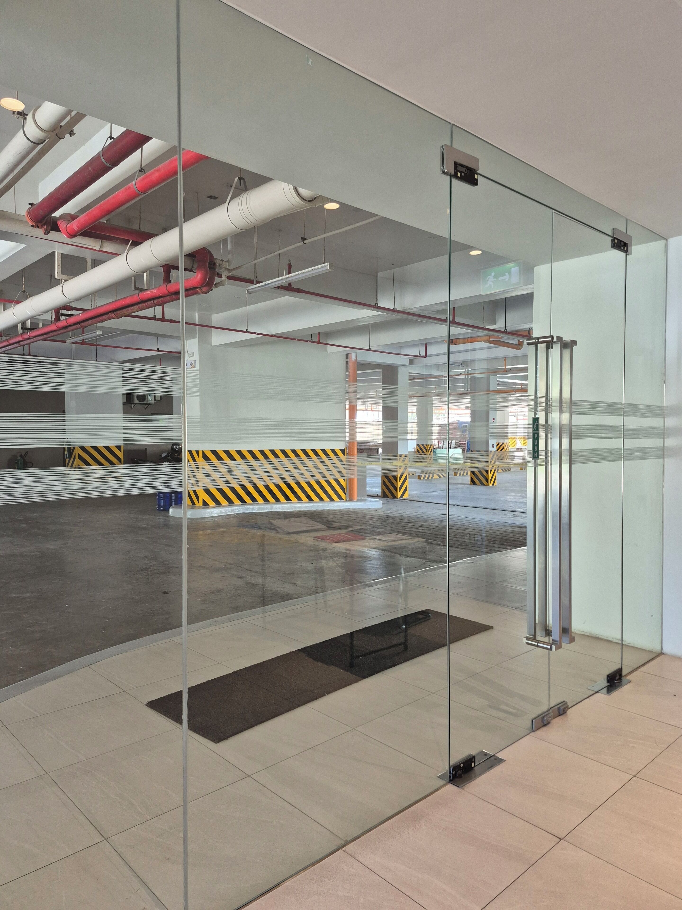 A modern interior with glass walls, a tiled floor, and visible industrial pipes.