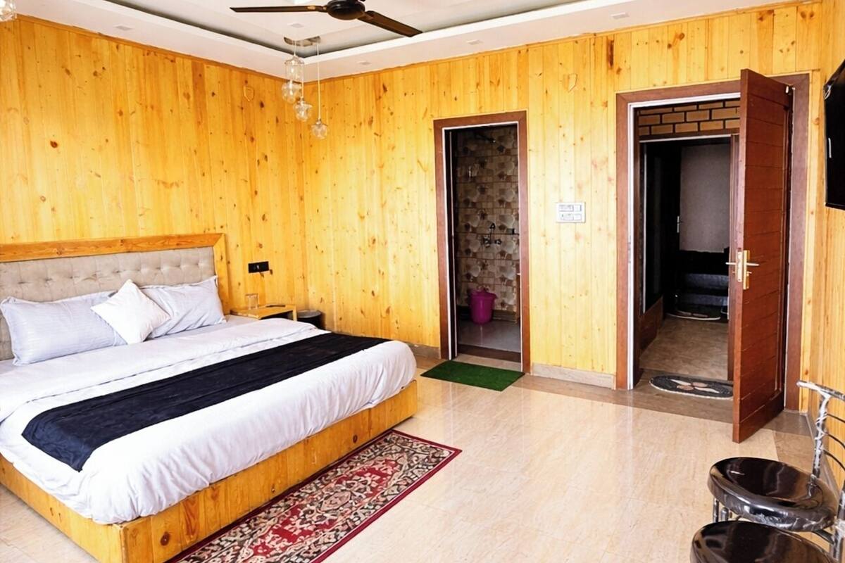 Een slaapkamer met een bed, een plafondventilator, een houten vloer en een deur die naar een andere kamer leidt.