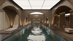 Una piscina interior moderna con pared de ladrillo, techos abovedados y zonas de estar.