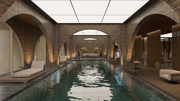 A modern indoor swimming pool with a brick wall, arched ceilings, and seating areas.