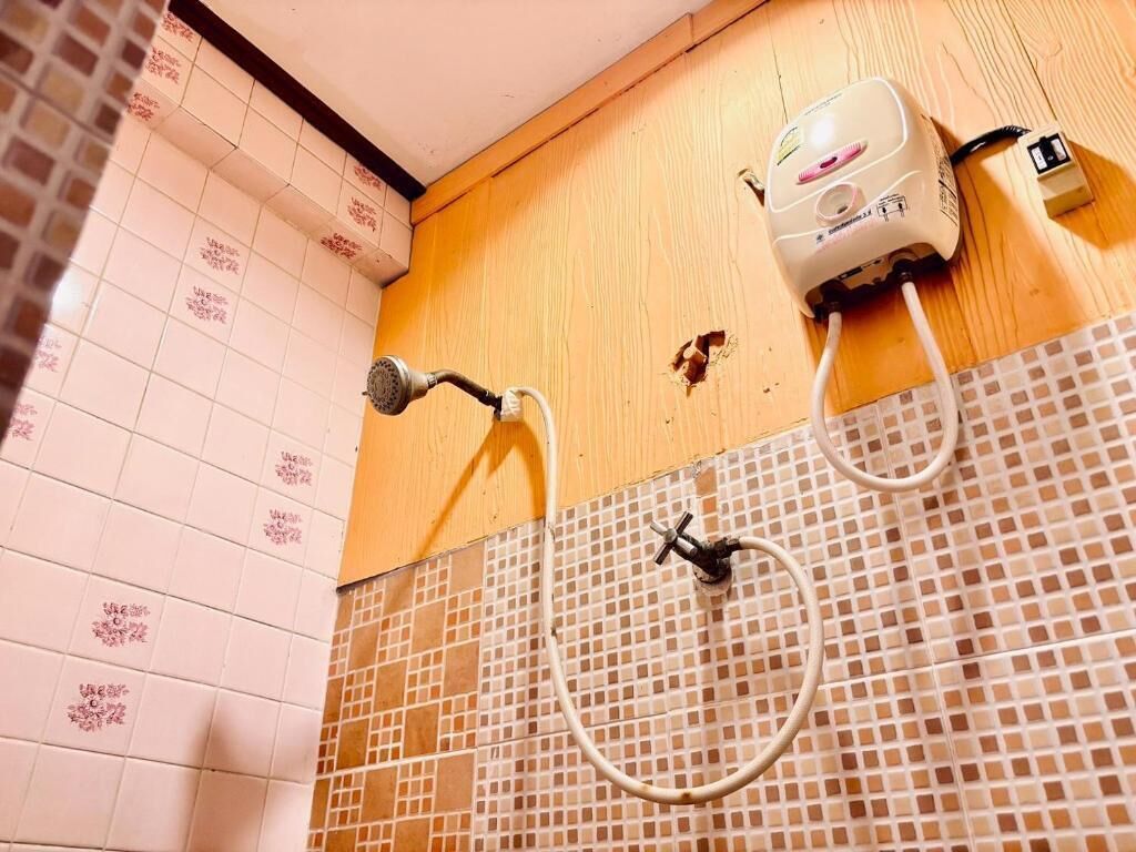 A bathroom with a tiled wall, a shower, and a water heater.