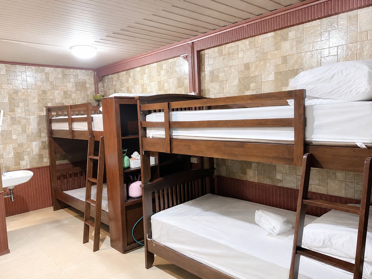 A bunk bed room with a sink and storage cabinets.