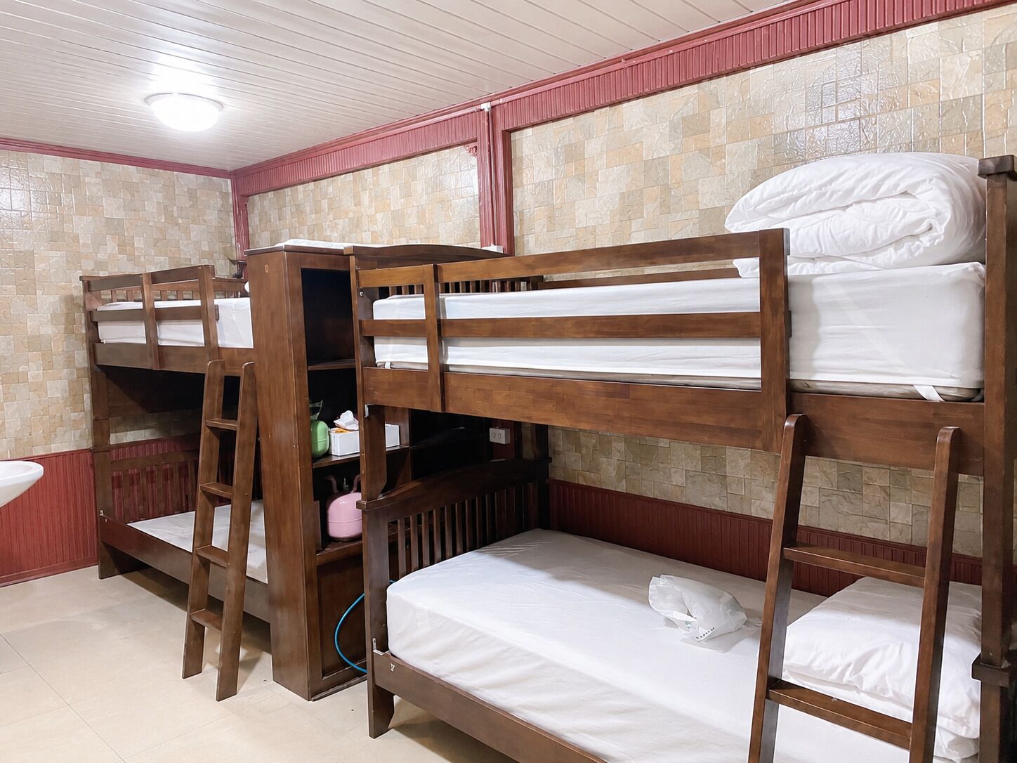 A room with bunk beds, a sink, and a tiled wall.