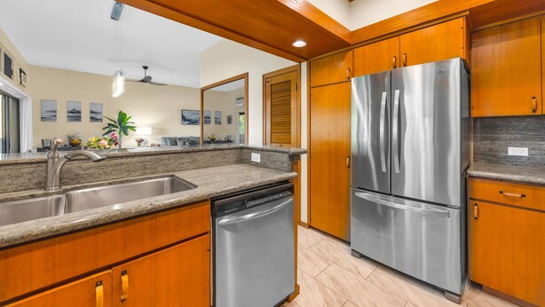 A modern kitchen with wooden cabinets, stainless steel appliances, and a granite countertop. - Kapalua Ridge | Ocean View 3 BR, Sleeps 12 | Car Incl. w/ 6+ Nights | KRV ML-3963 by KBM (Lahaina)